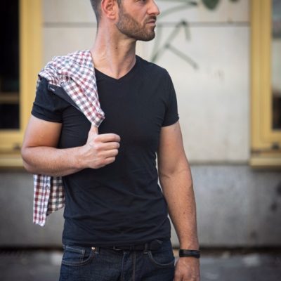 Attraktives männliches Model aus Berlin trägt ein Karohemd über der Schulter