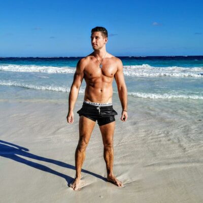 Callboy Chris W steht am Strand und zeigt seinen Körper