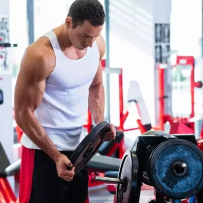 Callboy Ben trainiert im Fitness Studio in einem weißen Muskelshirt