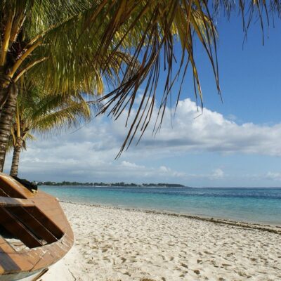 Die von Ihnen beschriebene Szene vermittelt mit ihrem friedlichen Zusammenspiel natürlicher Elemente ein Bild von Ruhe und Entspannung. Das Holzboot, eingebettet im Schatten der Palmen am Sandstrand, vermittelt ein Gefühl von Abenteuer und Freiheit. Es verkörpert die Einfachheit und den Charme, die oft mit abgeschiedenen Ausflügen verbunden werden. Der klare blaue Himmel, der im Hintergrund auf das türkisfarbene Meer trifft, unterstreicht diese ruhige Atmosphäre und lädt dazu ein, den Alltagsstress für einen Moment im Paradies hinter sich zu lassen. Die Einbeziehung eines „Callboys aus Madrid“ ruft einen faszinierenden Kontrast oder eine Hintergrundgeschichte hervor – vielleicht deutet sie auf Themen wie persönliche Transformation oder das Finden von Trost an unerwarteten Orten hin. Insgesamt ist es eine malerische Kulisse, ideal zum Nachdenken oder einfach zum Genießen der Schönheit der Natur.